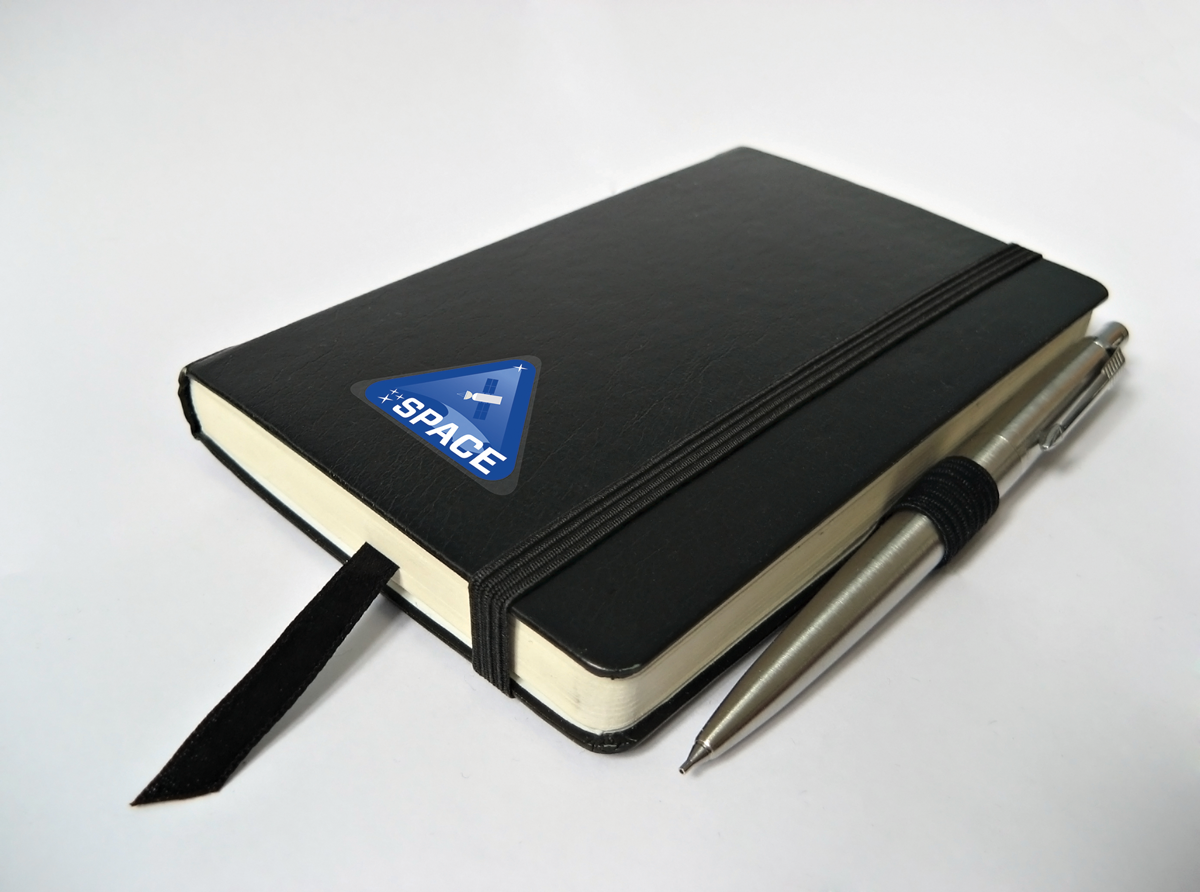 Moleskine journal with a triangular decal badge with the word Space written across it prominently.